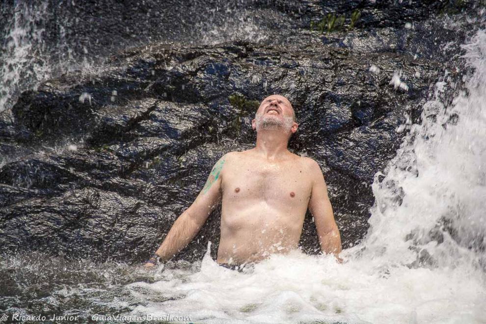 Imagem de um rapaz nas águas da cachoeira.